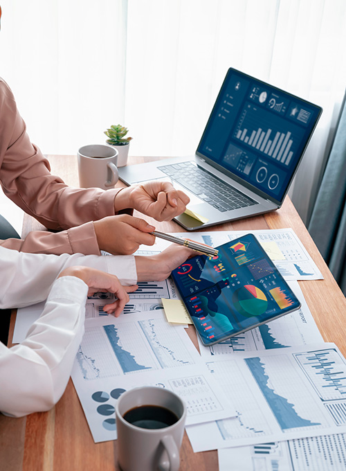 people at desk around laptop with stats on it
